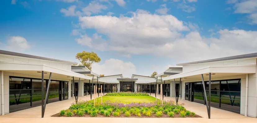 L'edificio moderno della Wirreanda Secondary School è circondato da un giardino ben curato e si staglia sotto un cielo azzurro con nuvole.