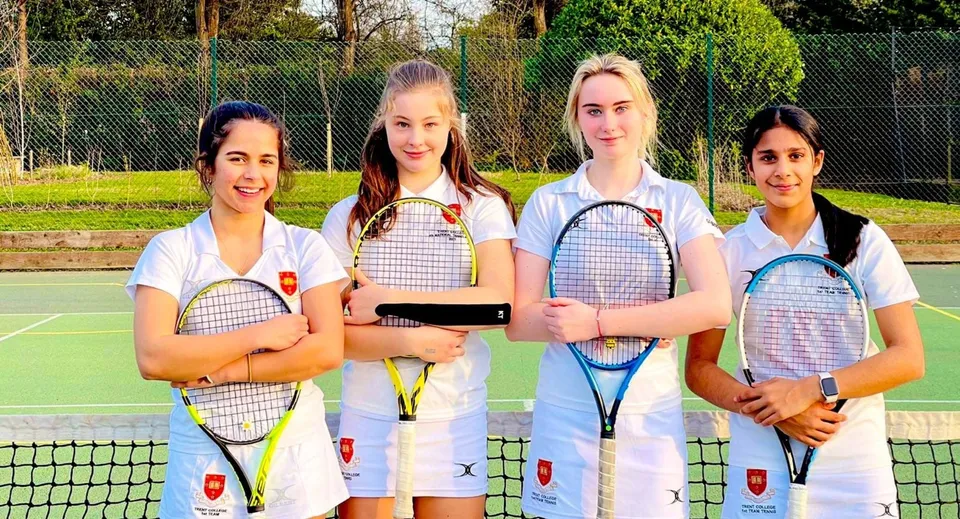 Quattro studentesse del Tettenhall College si trovano su un campo da tennis tenendo in mano delle racchette da tennis.