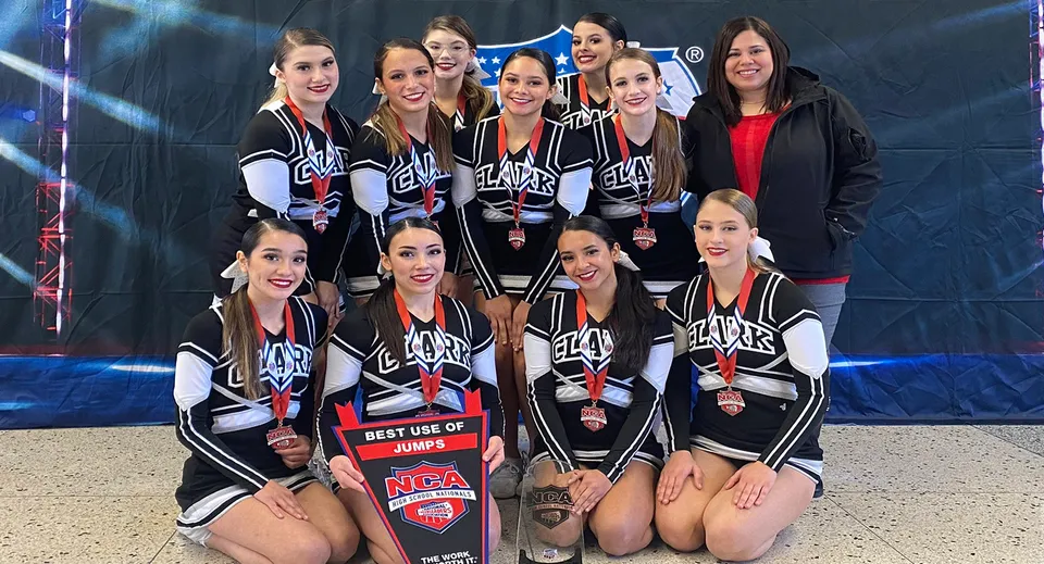 Un gruppo di cheerleader in divise coordinate bianche e nere posa insieme sul palco nel Clark County School District.