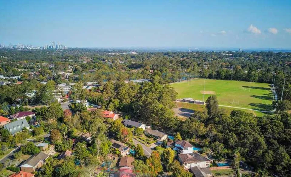 Vista su un'ampia area verde con bosco e case sullo sfondo della Ravenswood School for Girls.