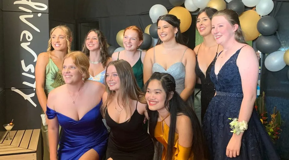Un gruppo di studentesse della Ballina Coast High School posa in abito formale davanti a dei palloncini durante una festa.