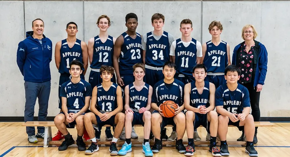 Un gruppo di studenti dell'Appleby College posa in divisa da basket in una palestra.
