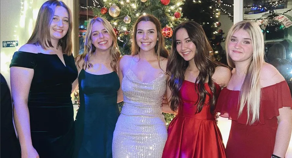 Cinque studentesse della Monterey Bay Academy posano insieme davanti a un albero di Natale decorato a festa.