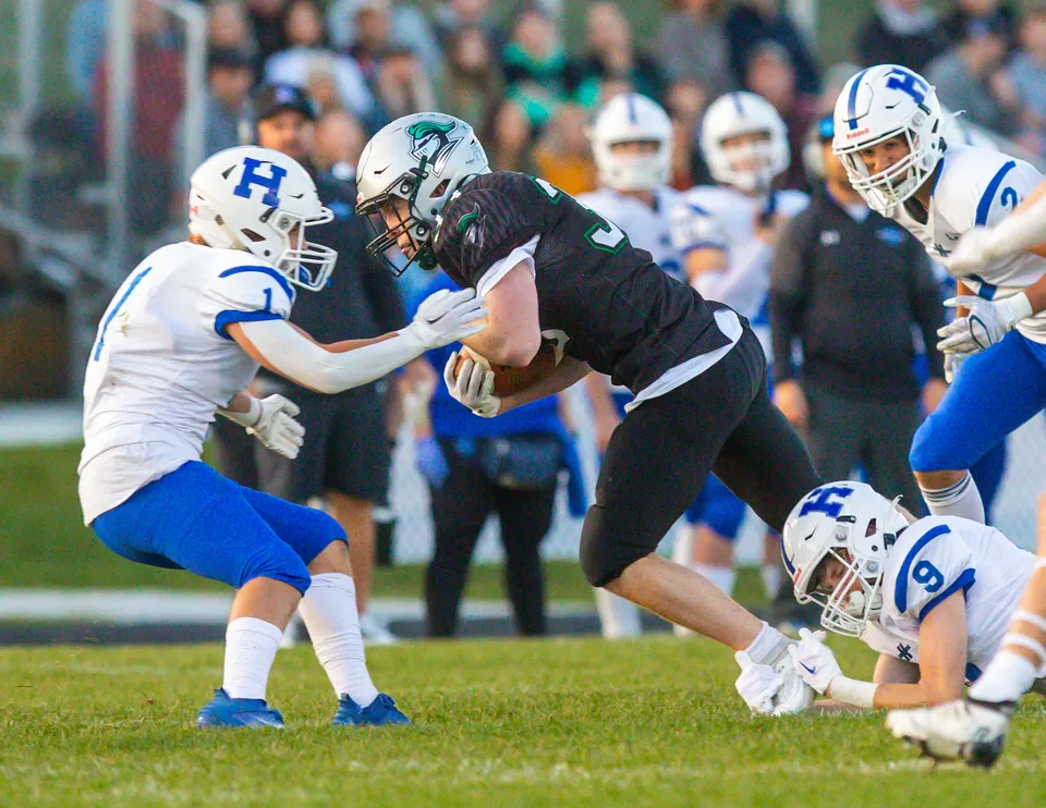 Due giocatori durante un tackle di football sul campo della Hunting Hills High School davanti al pubblico.