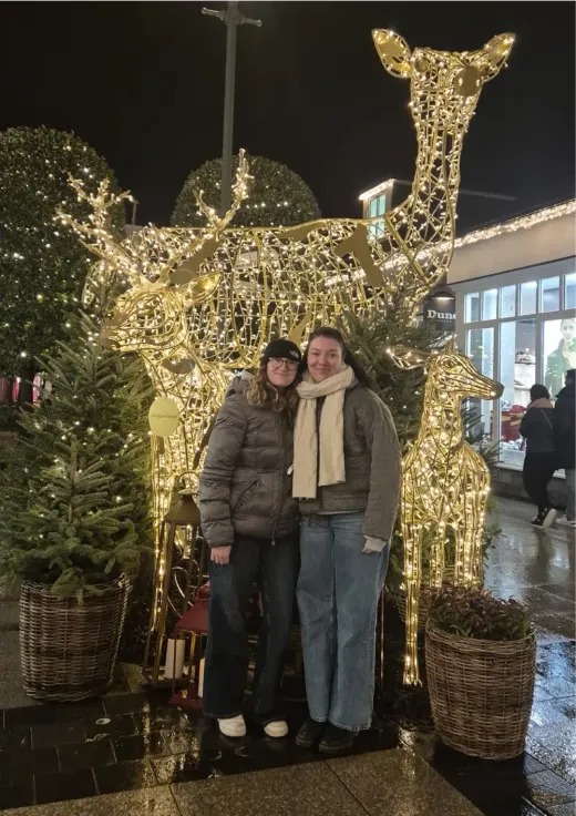 Zwei Mädchen umarmen sich vor leuchtenden Weihnachtsfiguren in Hirschform in Irland