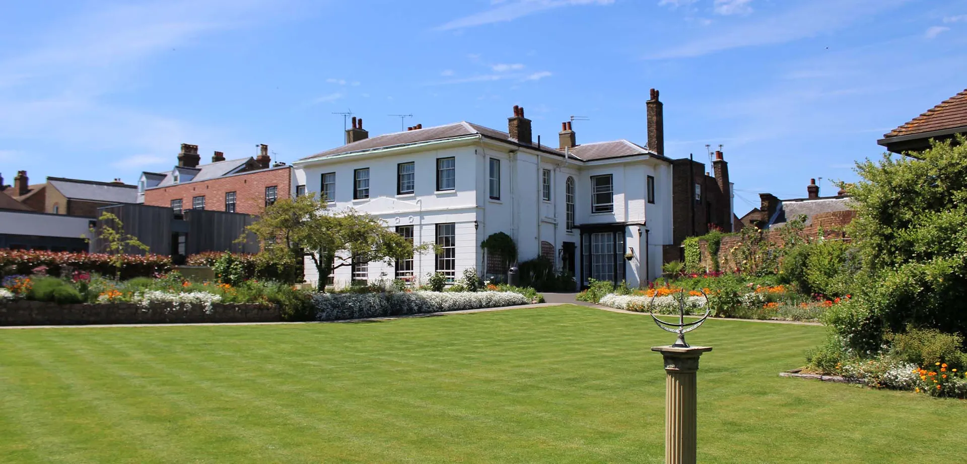 L'edificio bianco della King's School Rochester con un giardino curato e un prato verde.