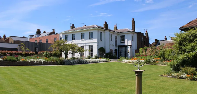 L'edificio bianco della King's School Rochester con un giardino curato e un prato verde.