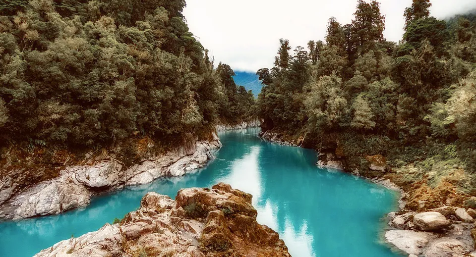 Un fiume turchese scorre attraverso un canyon boscoso con alte rocce nei pressi del Selwyn College.