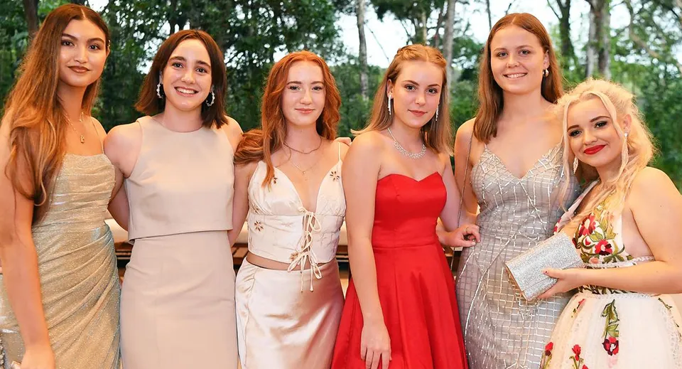 Sei studentesse della Sunshine Beach State High School posano insieme all'aperto in abiti da sera eleganti.
