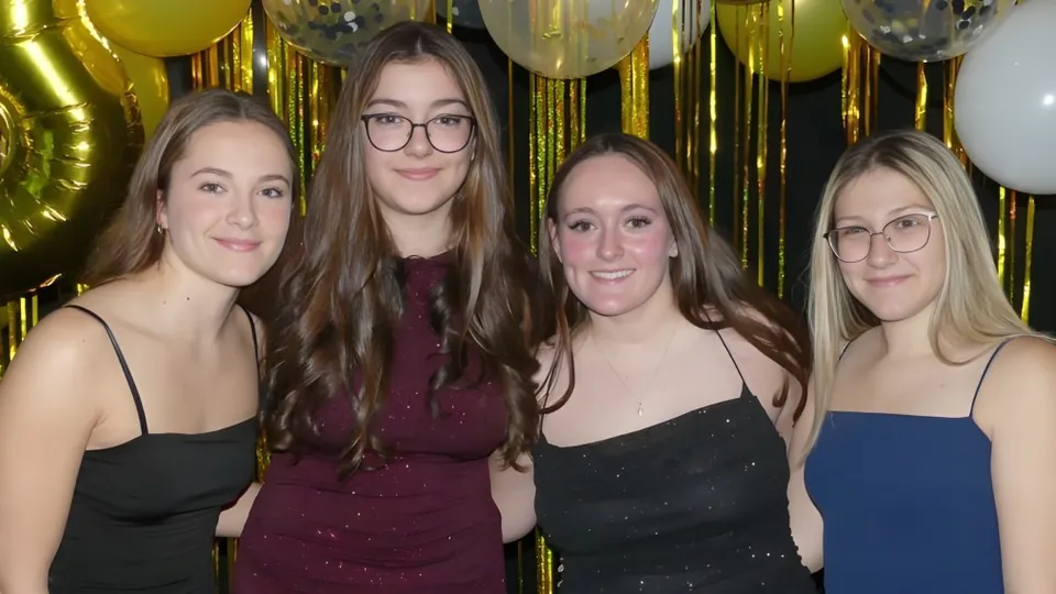 Quattro studentesse in abito formale posano davanti a palloncini dorati e d'argento sul campus della École Clément-Cormier.