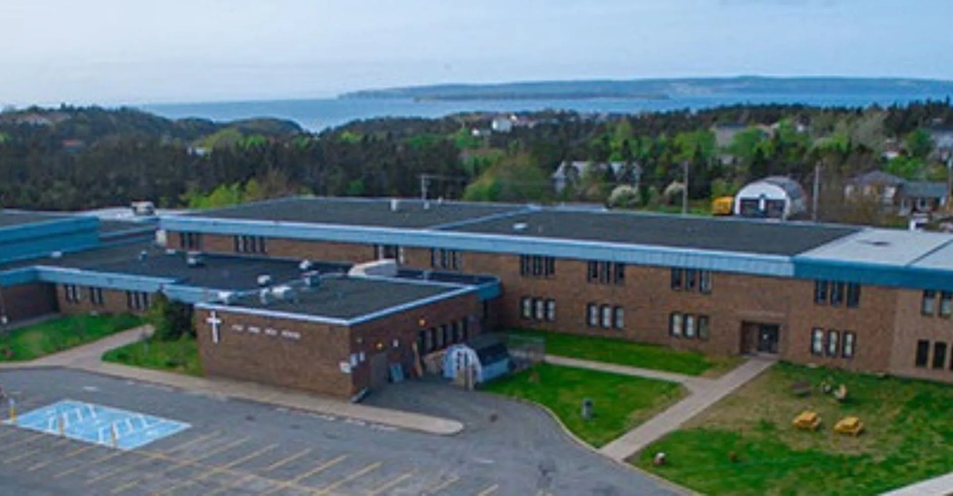 L'edificio in mattoni a più piani della Holy Spirit High School si trova in un campus verdeggiante con vista su uno specchio d'acqua.