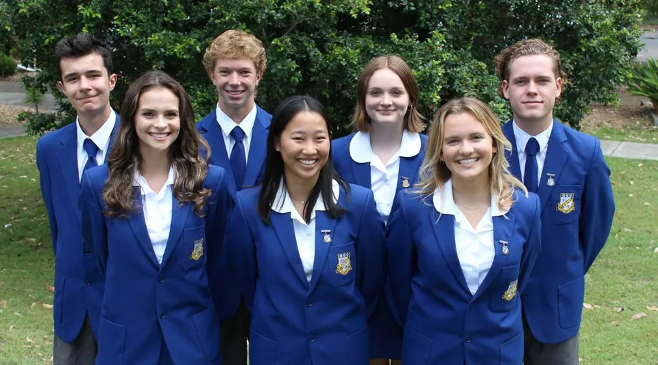 Un gruppo di studenti della Narrabeen Sports High School insieme su un prato con alberi sullo sfondo.