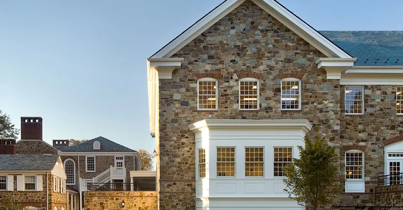 L'imponente edificio in pietra della The Bryn Mawr School si erge sotto un cielo azzurro e limpido con edifici più piccoli sullo sfondo.