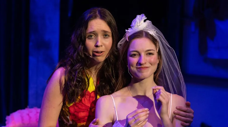Due donne in piedi insieme su un palco con sfondo blu nel campus della Millbrook School.