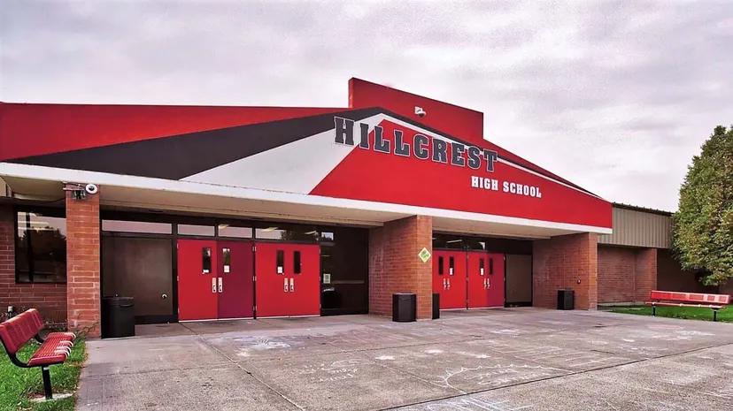 L'edificio principale rosso e nero della Hillcrest High School davanti a un cielo nuvoloso.