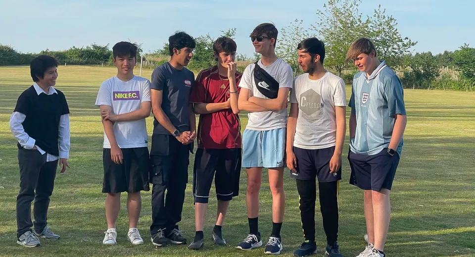 Un gruppo di studenti della Brookes UK si trova insieme su un prato con alberi sullo sfondo.