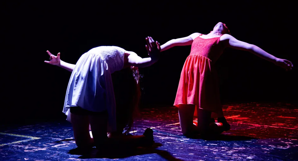 Estudiantes de la St. Edward's School en Poole presentan una obra de teatro dramática en un escenario con suelo estampado.