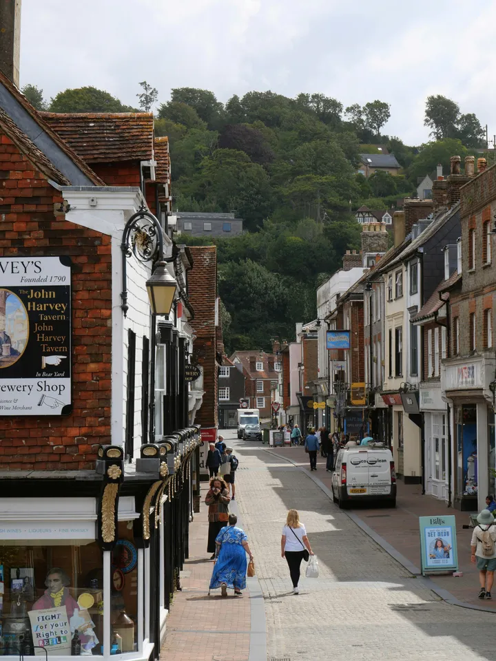 Historische Einkaufsstraße in Lewes mit Fachwerkhäusern und grünem Hügel im Hintergrund