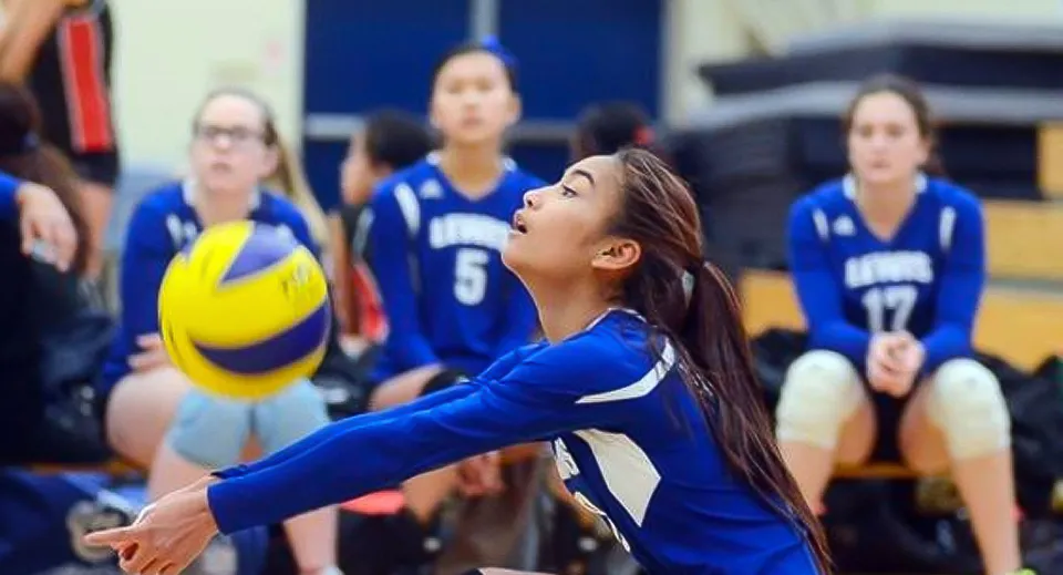Una giocatrice di pallavolo della Stephen Lewis Secondary School riceve un pallone in palestra.