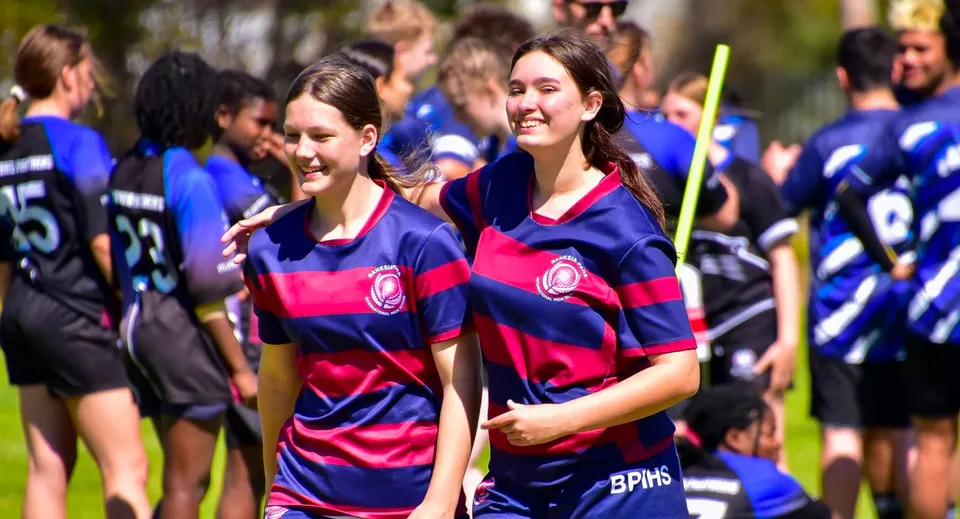 Un gruppo di studenti e studentesse della Banksia Park International High School sta insieme all'aperto indossando divise sportive abbinate.