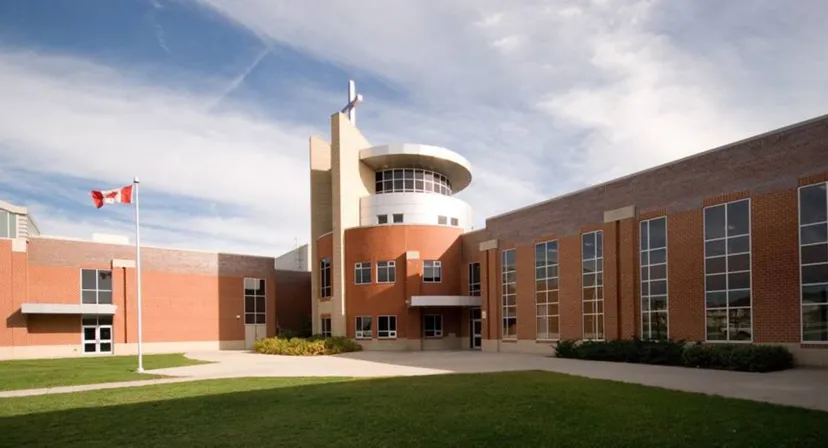 L'edificio moderno a più piani della John McCrae Secondary School con la bandiera canadese e un prato ben curato in primo piano.