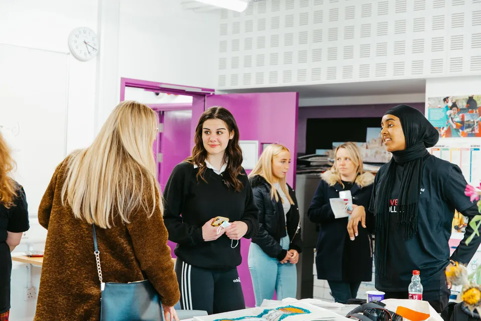 Un gruppo di studentesse di The Sheffield College si trova in un corridoio con una parete rosa sullo sfondo.
