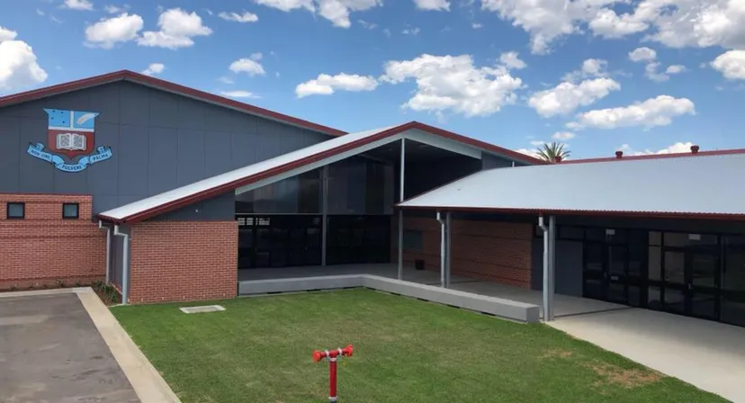 L'edificio moderno in mattoni della Maryborough State High School si trova su un prato sotto un cielo blu con nuvole bianche.