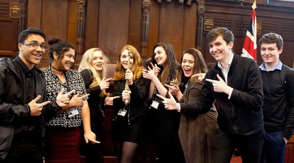 Un gruppo di studenti si trova al National Mathematics and Science College davanti a una boiserie storica in legno.