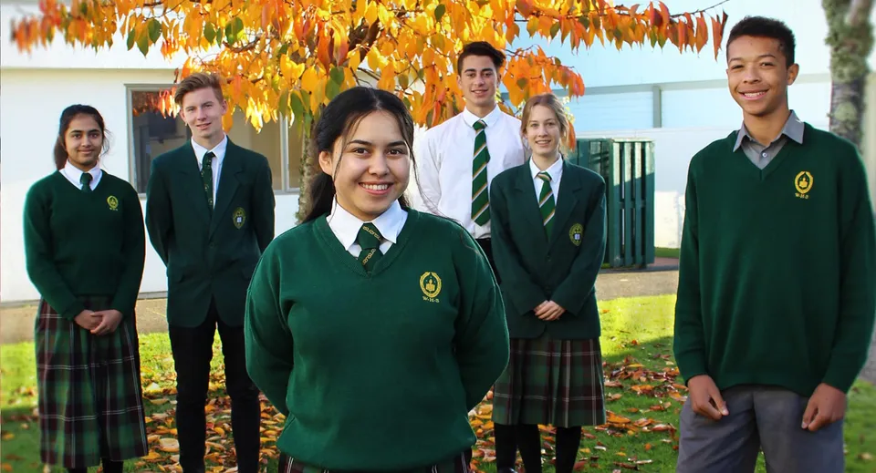 Un gruppo di studentesse e studenti della Whanganui High School in piedi davanti a foglie autunnali.