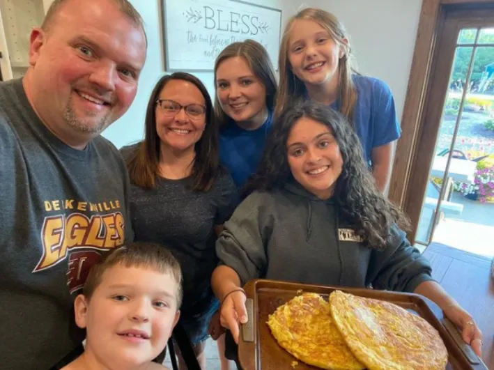 Familia sonriente posando en grupo mientras una chica sostiene una bandeja con tortillas de patatas