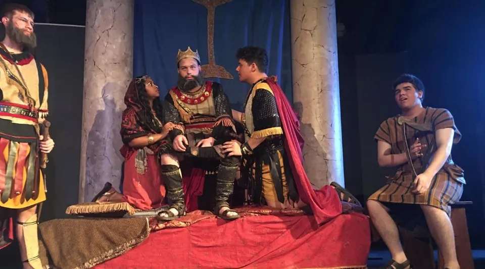 Studenti della Our Savior New American School mettono in scena una rappresentazione teatrale con attori in costume su un palco.