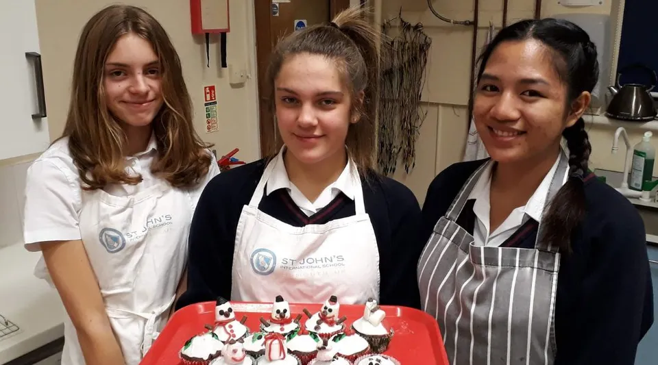 Tre studentesse della St. John’s School Sidmouth sono insieme nella cucina della scuola.