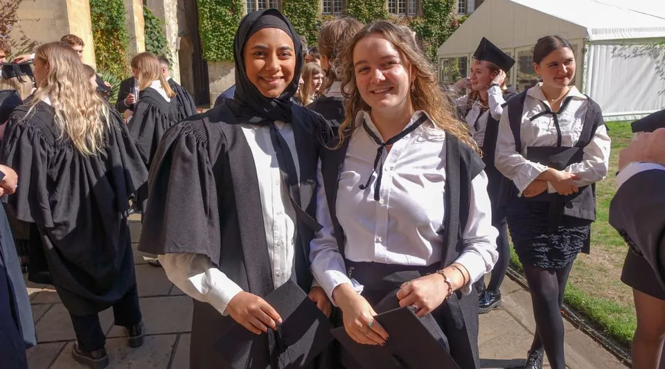 Un gruppo di giovani laureate in abito accademico nel campus dell'Exeter College.