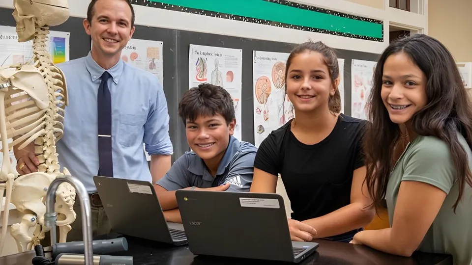 Studenti e un docente della St. Joseph High School lavorano insieme a un laptop in un'aula con modelli anatomici.