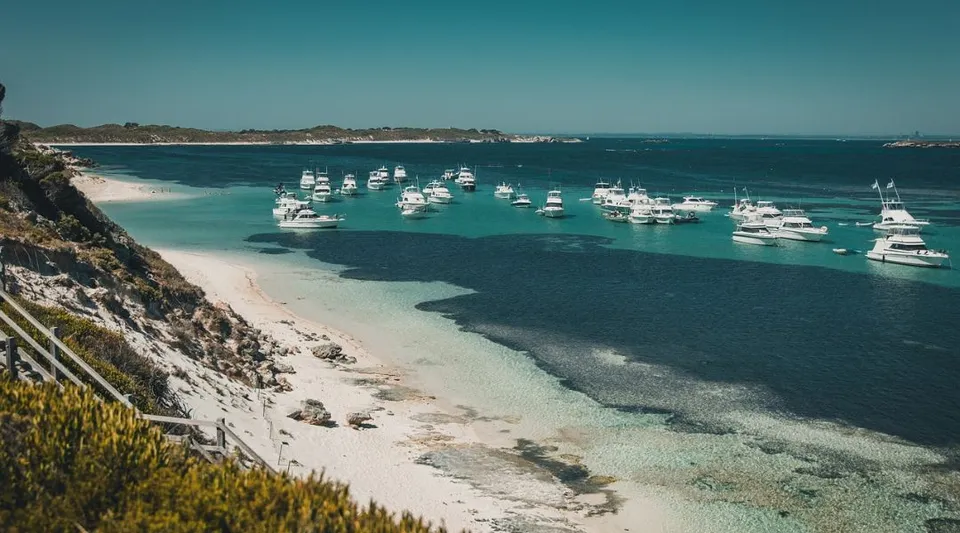 Il paesaggio costiero con una tranquilla baia turchese e barche davanti al Mindarie Senior College.