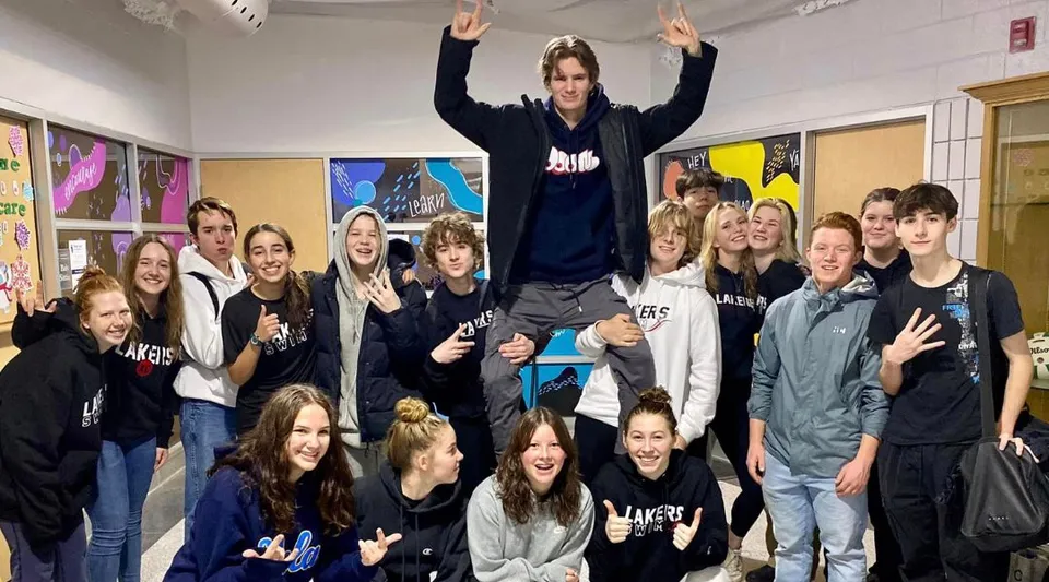 Un gruppo di studenti della Bracebridge and Muskoka Lakes Secondary School posa in un'aula con poster colorati alla parete.