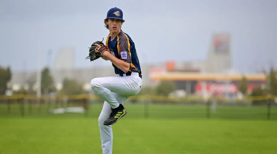 Un giocatore di baseball sta sul campo della Hampton Senior High School davanti a uno sfondo urbano.