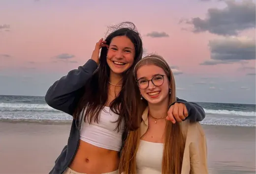 Luisa und eine Freundin lächeln bei Sonnenuntergang am Strand in Australien