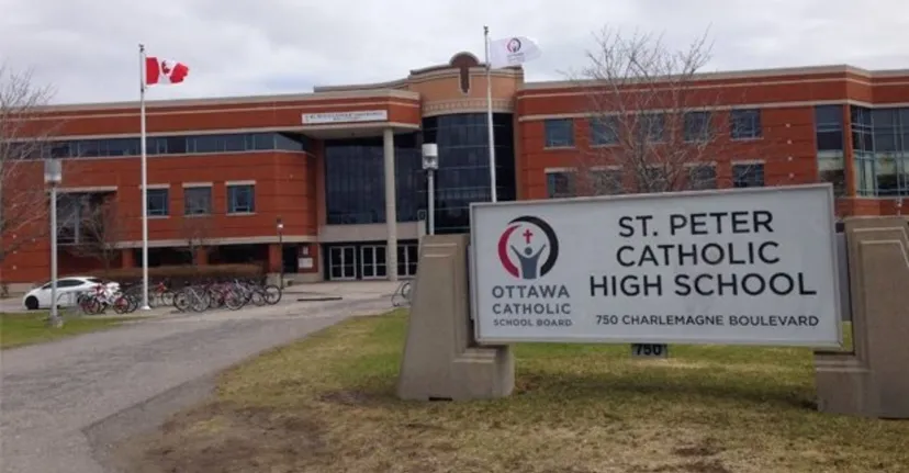 L'edificio in mattoni della St. Peter Catholic High School con la bandiera canadese e biciclette parcheggiate davanti.