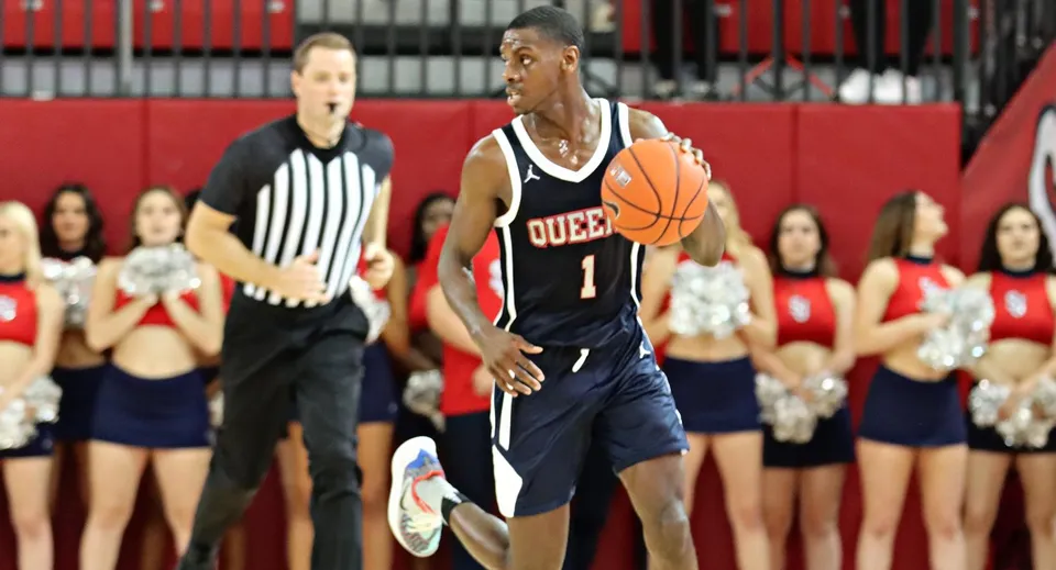 Un giocatore di pallacanestro del Queen’s College corre con la palla durante una partita in palestra.