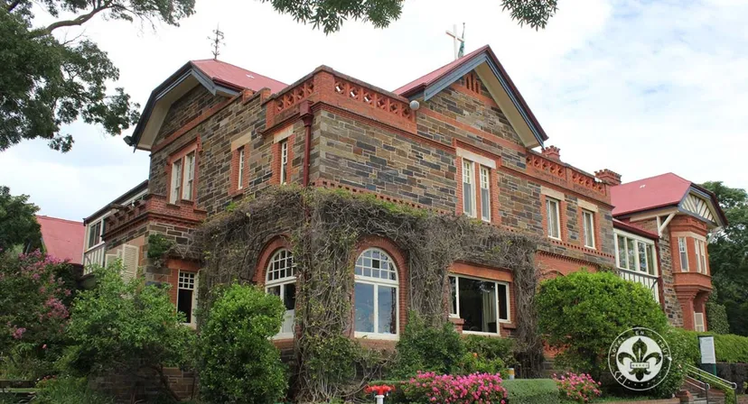 L'appariscente edificio in mattoni con tetto in tegole rosse nel campus del Mercedes College è circondato da alberi.
