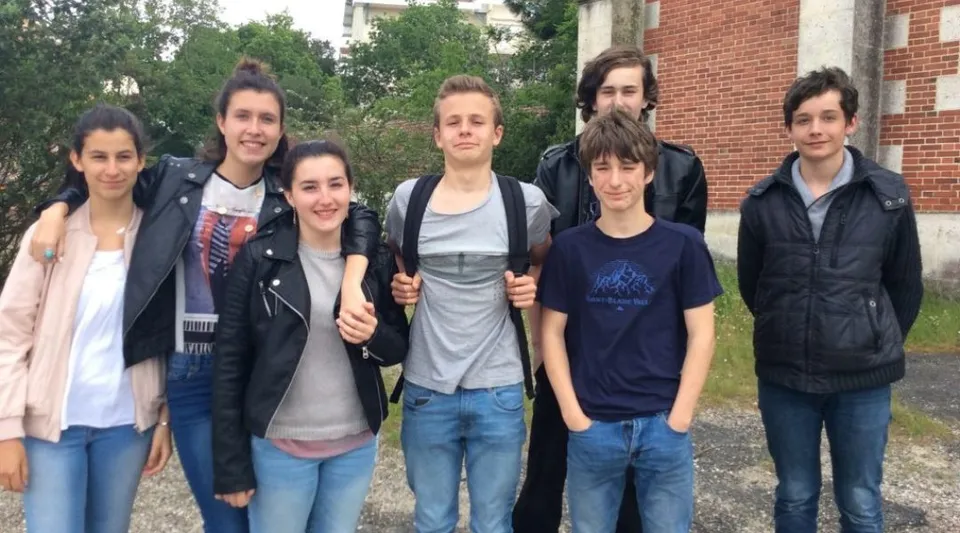 Un gruppo di studenti e studentesse si trova davanti a un edificio in mattoni nel campus del Lycée St Elme.