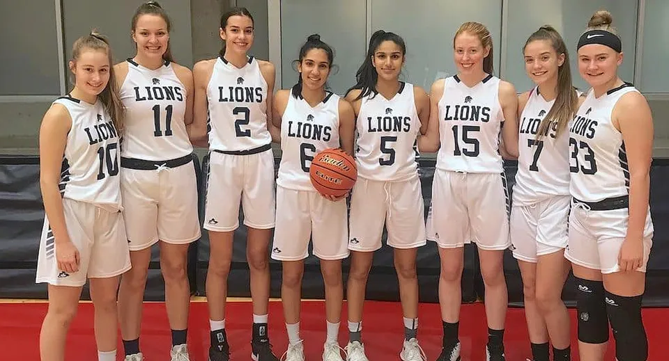 Un gruppo di giocatrici di basket della Yale Secondary School stanno insieme e tengono un pallone da basket.