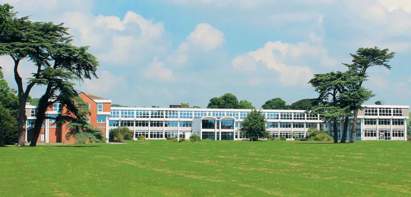 L'edificio moderno del Worthing College è circondato da un prato verde e da alberi.