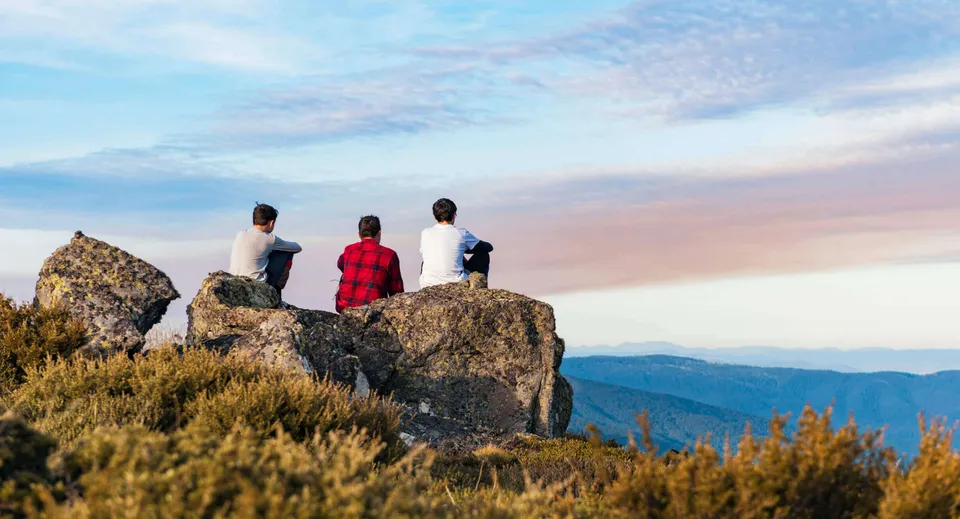 Tre persone sono in piedi su una roccia e guardano il paesaggio montano vicino alla Malanda State High School.