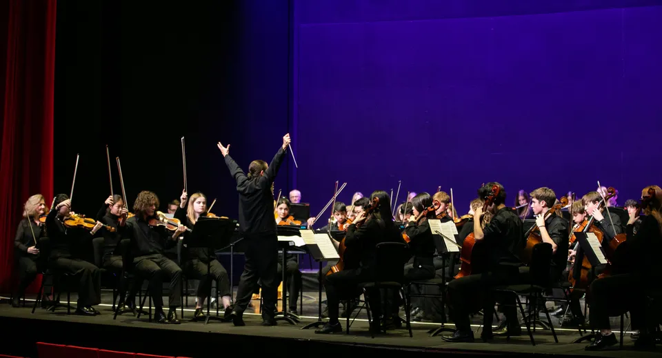 L'orchestra della Westonbirt School suona sul palco sotto la direzione di un direttore d'orchestra.