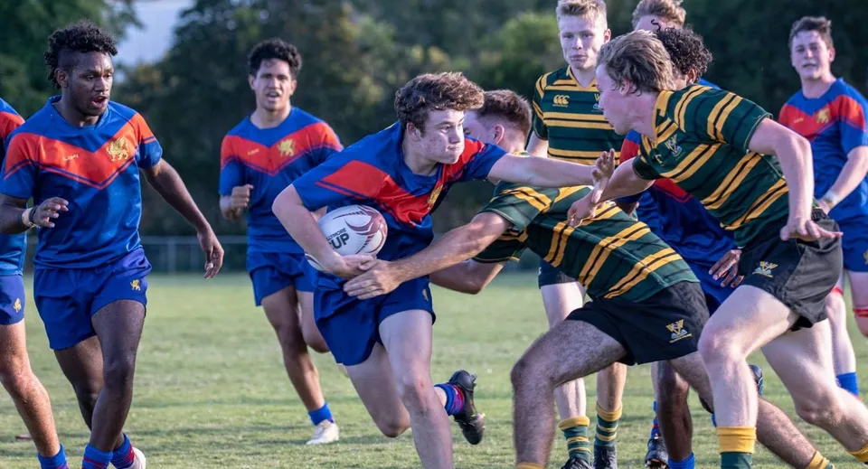 Studenti della Townsville Grammar School giocano un'intensa partita di rugby su un campo in erba.