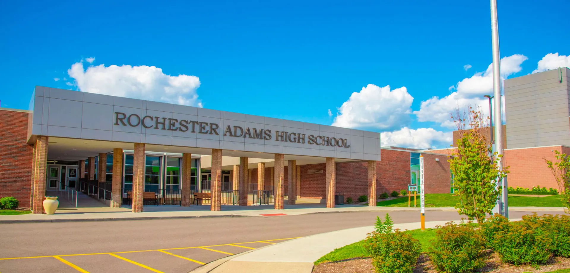 Il grande edificio in mattoni delle Rochester Community Schools sotto un cielo blu con nuvole bianche.