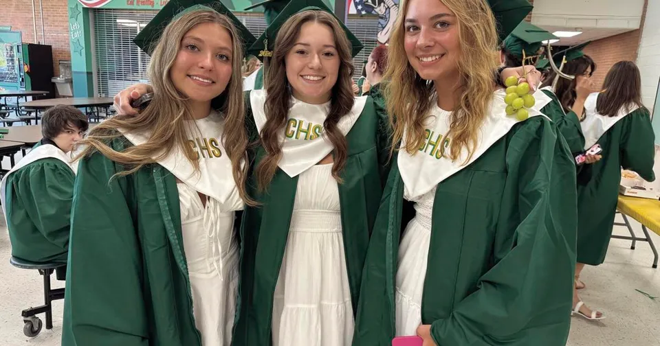 Tre studentesse in toga verde da diploma mettono in posa insieme per una foto nel campus della Coventry High School.