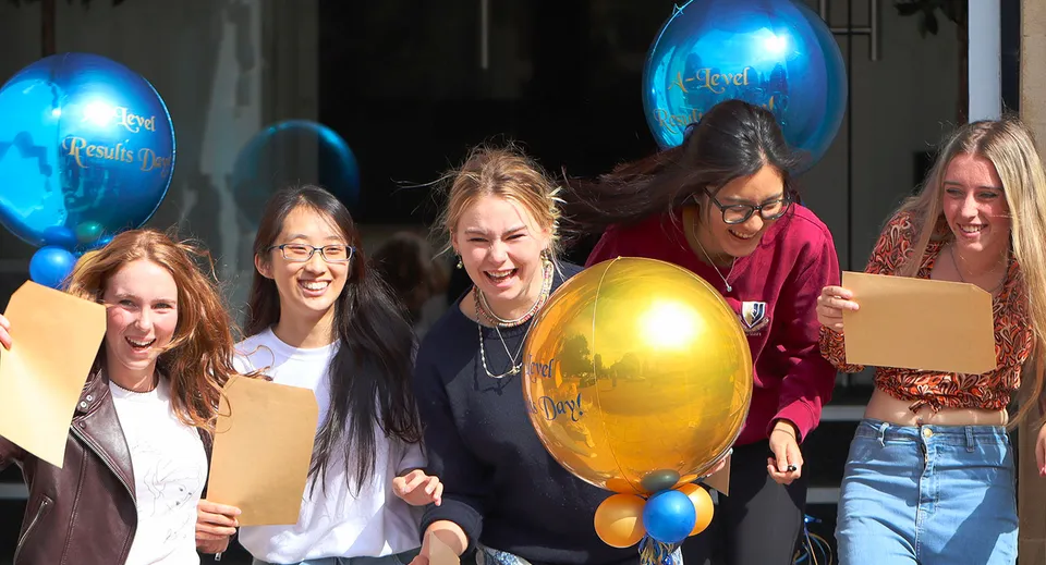 Un gruppo di studentesse della Malvern St. James Girls' School festeggia con palloncini colorati durante un evento al coperto.